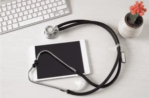 A stethoscope on an iPad with a keyboard and plant