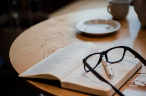 Open notebook beside a coffee cup on a wooden desk