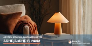 Blog post: ADHD/AuDHD Burnout Is Not the Same as Being Tired — a warm brass table lamp lit at dusk with a folded throw on an armchair, representing the nervous system coming down after running on empty